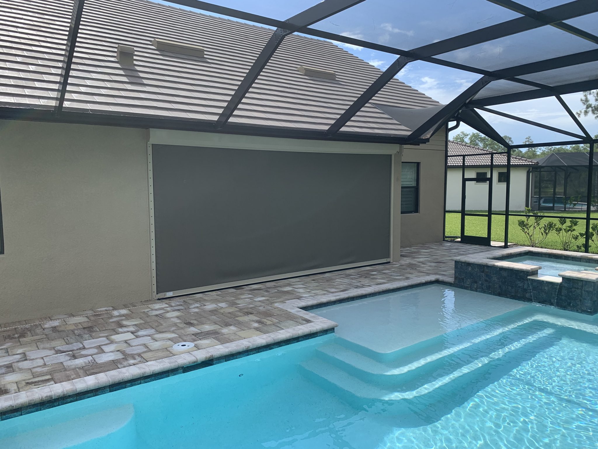 Large roll-down screen lowered beside a Florida pool lanai