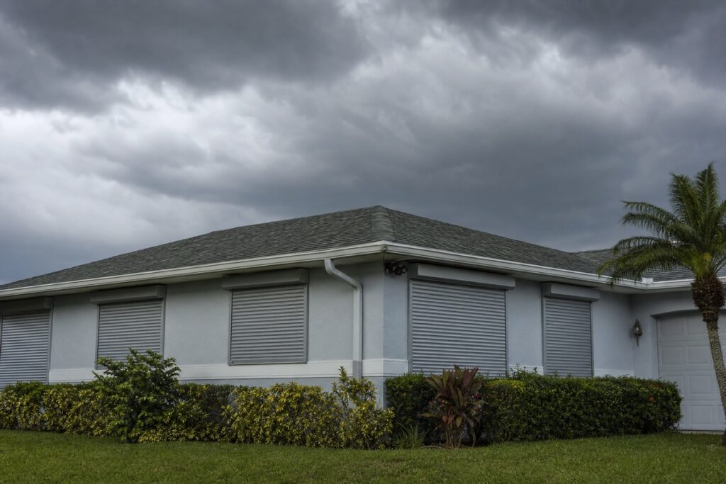 Closed storm shutters on a Florida home under a pre-storm sky