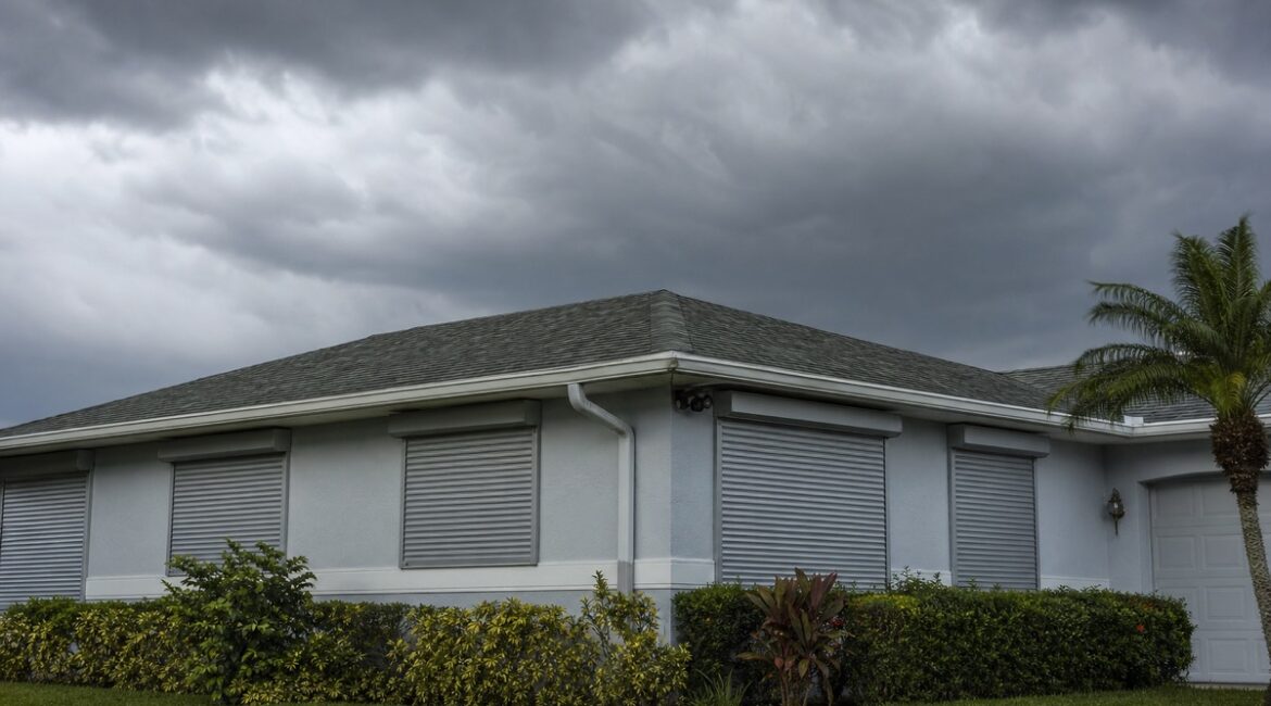 Closed storm shutters on a Florida home under a pre-storm sky