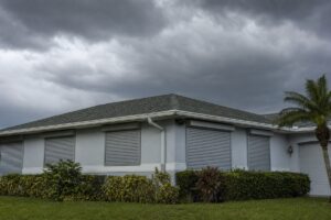 Closed storm shutters on a Florida home under a pre-storm sky