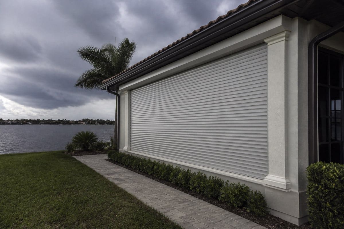 Motorized roll-down hurricane shutter fully closed over a waterfront lanai opening